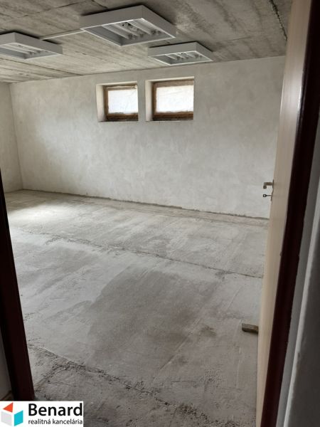 Unfurnished room in a family house with two small windows and a raw floor.