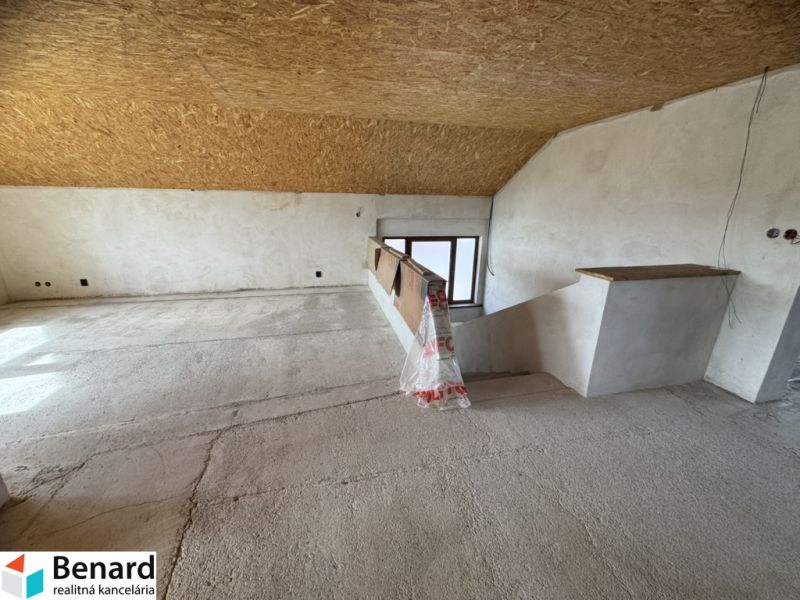 The attic of a family house with a wooden ceiling and a view of the interior staircase.