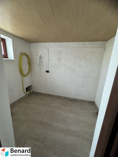 Laundry room with tiled floor and ceiling with wooden decor in a family house.