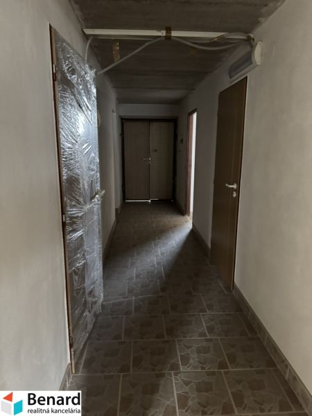 A hallway in a family house, with beige tiles on the floor and plastic doors.