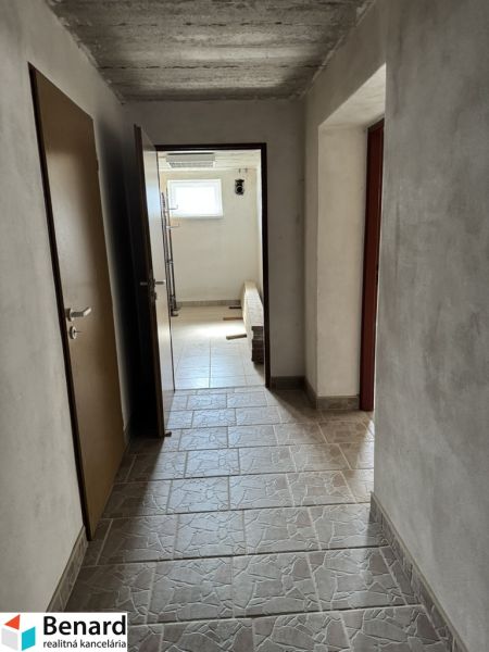 A hallway in a family house with tiles and a window, without visible furniture.