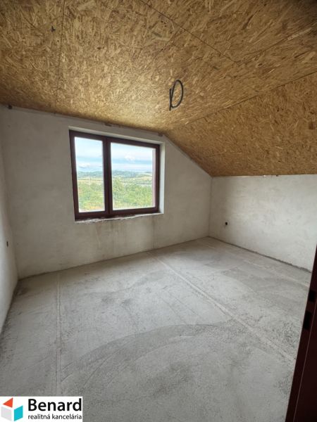 A view into an empty room of a family house with a skylight and a concrete floor.