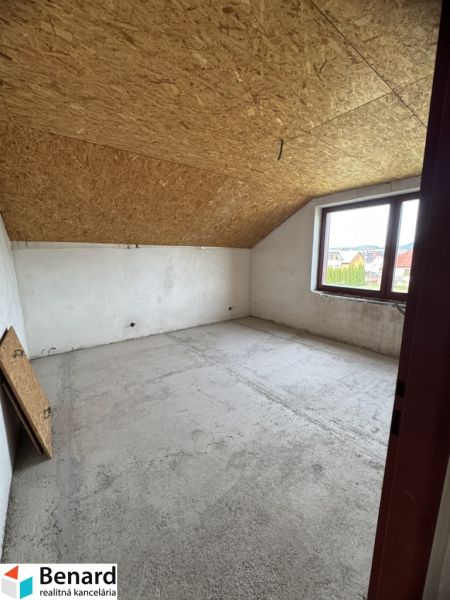 Attic room in a family house with a wooden ceiling and a large window.