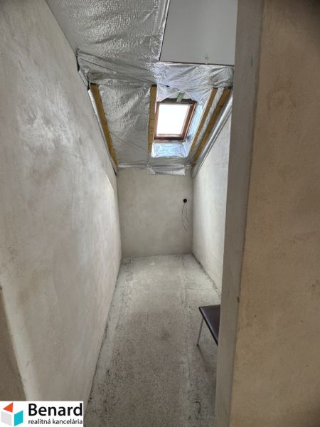 A narrow room with a concrete floor and a skylight in a family house.