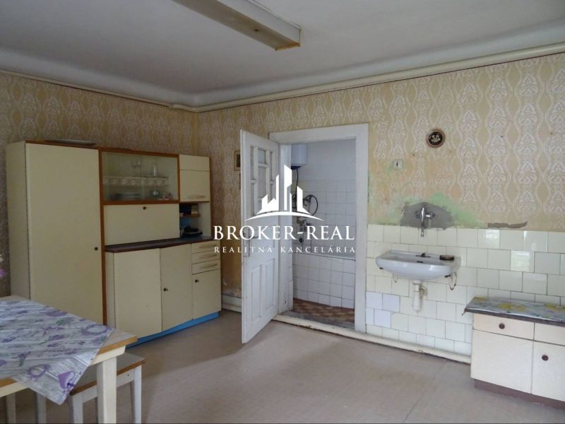A kitchen in a family house with vintage furniture and a sink, floor with wooden decor.