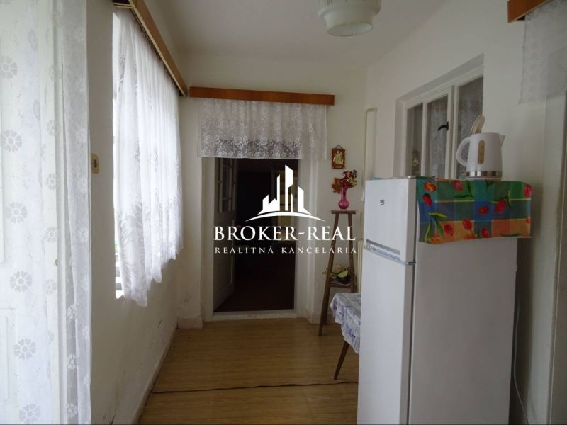Interior of a family house with a white refrigerator and a floor decorated with a wooden pattern.