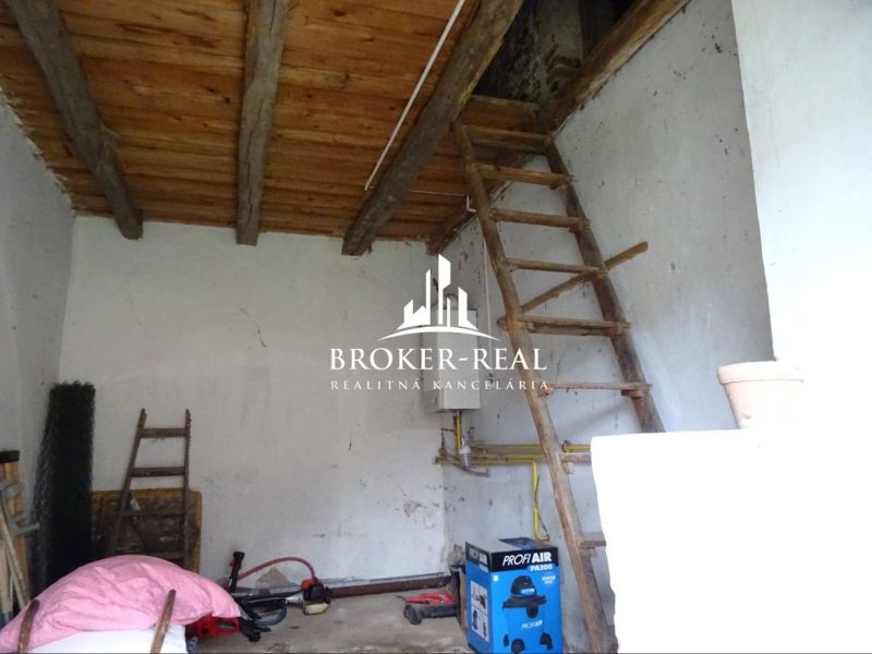 Interior of a family house with a wooden ceiling and a ladder, furnished with tools and crates.