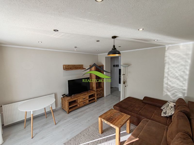 Living room in a 3-room apartment with a sofa and wooden decor furniture.
