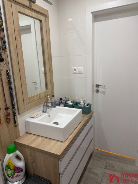 A bathroom in a 2-room apartment with a sink and furniture with a wood decor.