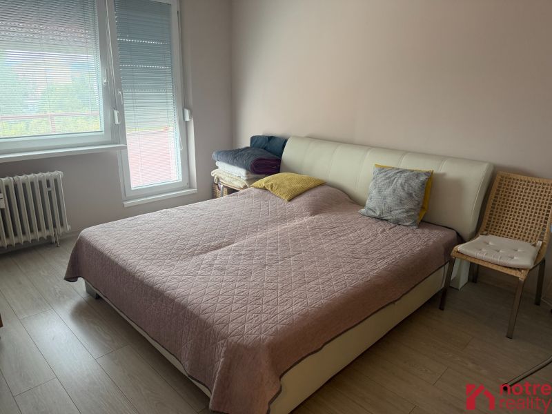 Bedroom with a bed, wooden floor decor, and a chair in a two-room apartment.