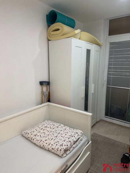 A room with a bed, wardrobe, and rolled-up mattresses in a 2-room apartment.