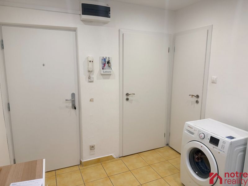 Entrance hallway in a 2-room apartment with yellow tiles and a washing machine.