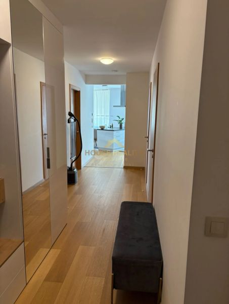 A hallway with a wooden decor floor and a mirror in a 3-room apartment.
