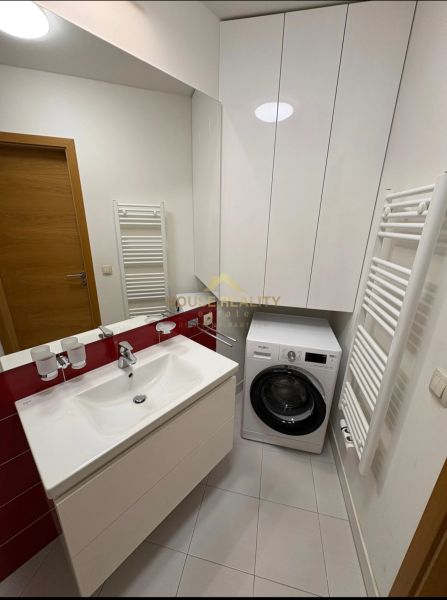 A bathroom in a 3-room apartment with a washing machine, sink, and storage space.