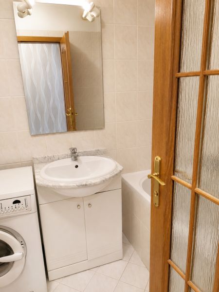 Bathroom in a 2-room apartment with a washing machine, sink, and bathtub.