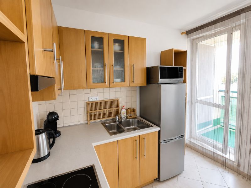 A kitchen with wooden cabinets, a refrigerator, and a microwave in a two-room apartment.