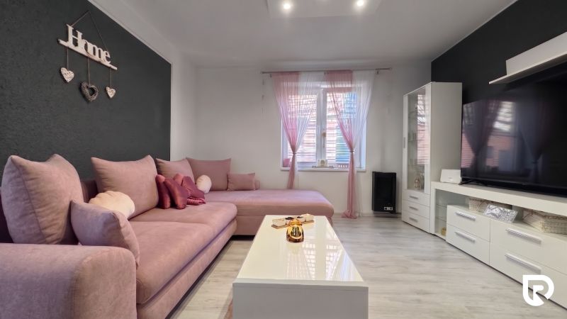 Living room in a family house with a pink sofa and white furniture.