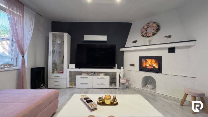 Living room with a fireplace, television, and wood-patterned flooring in a family house.