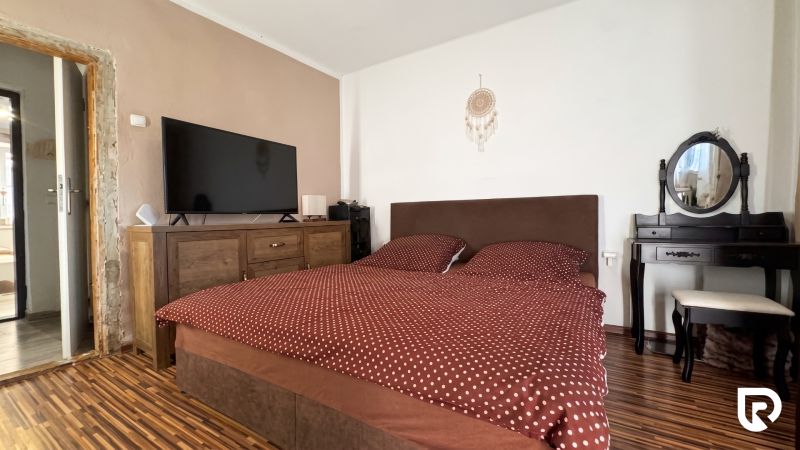 Bedroom in a family house with a TV, dresser, bed, and floor with a wood decor.