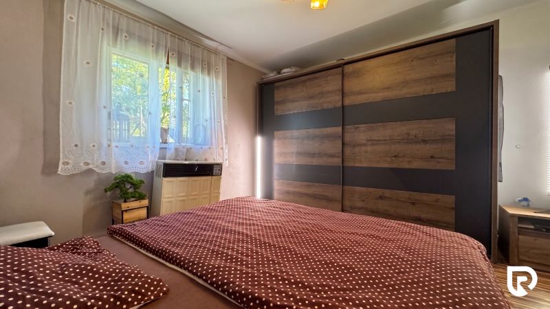 Bedroom in a family house with a large wardrobe and a bed with a polka dot blanket.