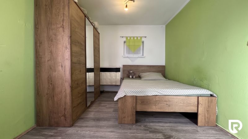 A bedroom in a family house with a bed, a wardrobe, and a floor with a wooden decor.