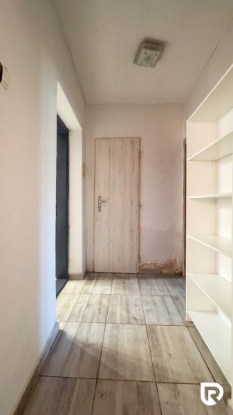 A hallway in a family house with tiles and a white bookshelf.