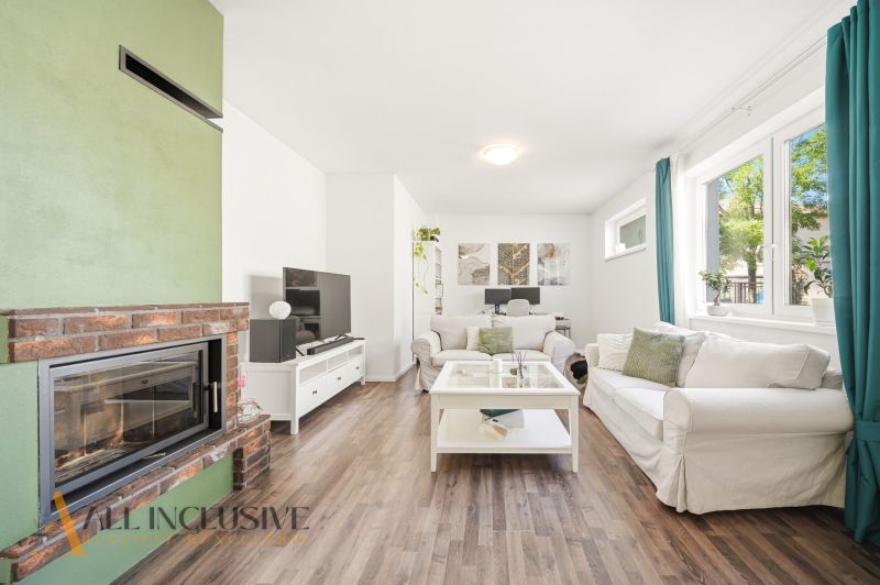 Living room with a fireplace, TV stand, and wooden decor flooring in a three-room apartment.