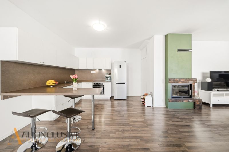 A kitchen in a 3-room apartment with a bar counter, a fireplace, and a floor with a wooden decor.