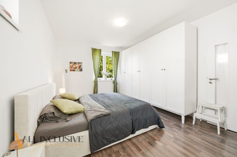 A bright bedroom with a large bed, wardrobe, and wooden decor flooring in a 3-room apartment.