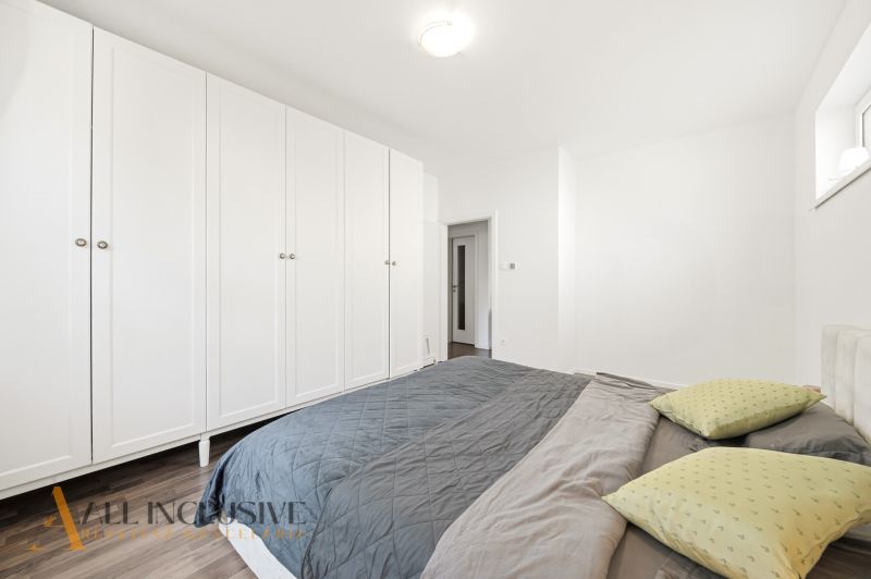 A bedroom in a three-room apartment with a white wardrobe and a wooden decor floor.