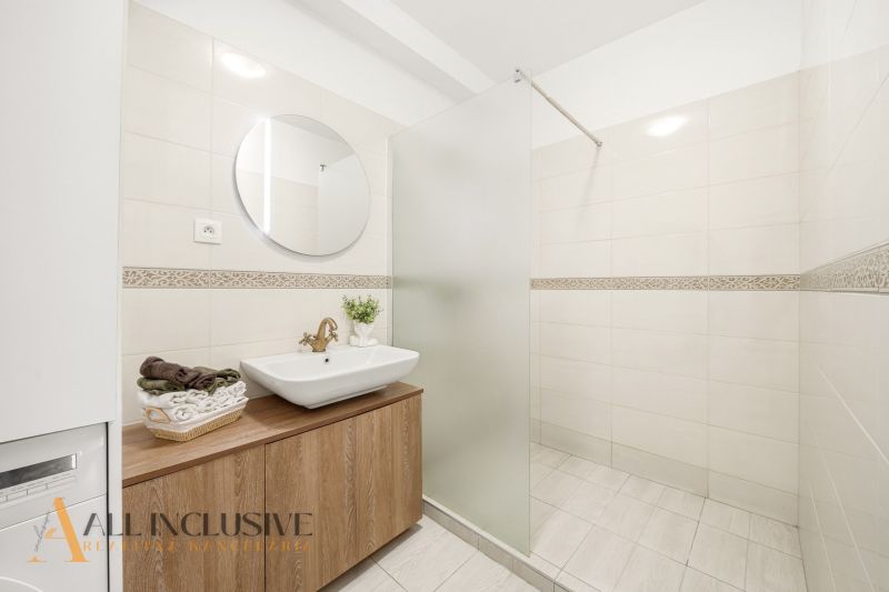 Bathroom in a 3-room apartment with a sink, mirror, and shower corner, white tiles.