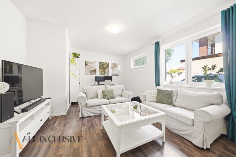 A bright living room with white furniture and a wooden decor floor in a 3-room apartment.