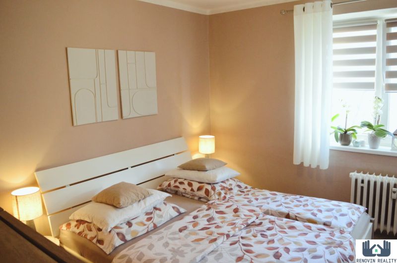 A bedroom with two beds and decorative paintings in a three-room apartment.