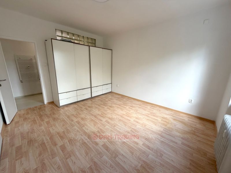 A room in a 2-room apartment with a wooden decor floor and a large wardrobe.