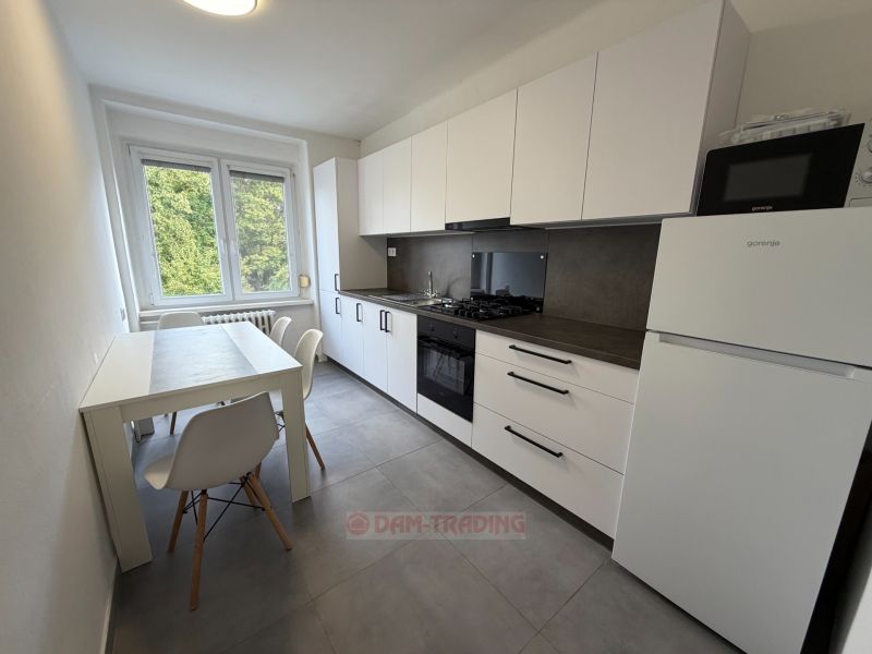The kitchen in a 2-room apartment with a light dining table and white cabinets.