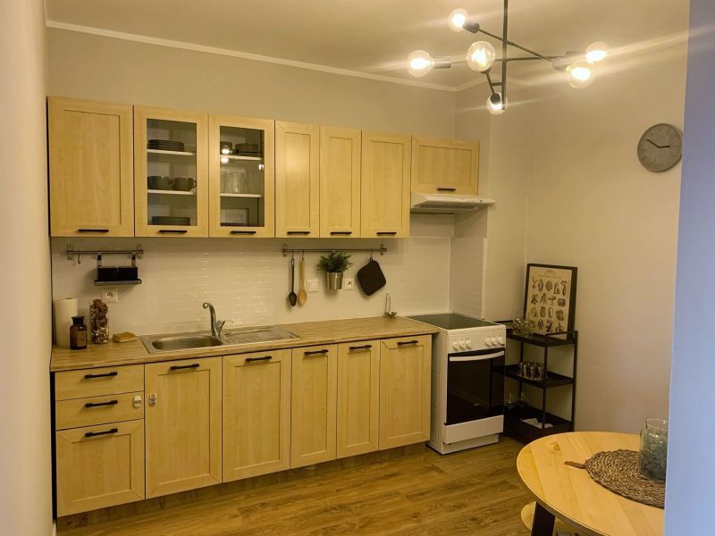 A kitchen in a 2-room apartment with a wooden decor and a light kitchen unit.