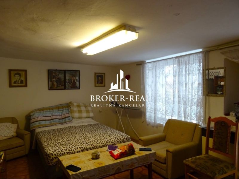 Interior of a family house with a dining table, bed, and chairs.