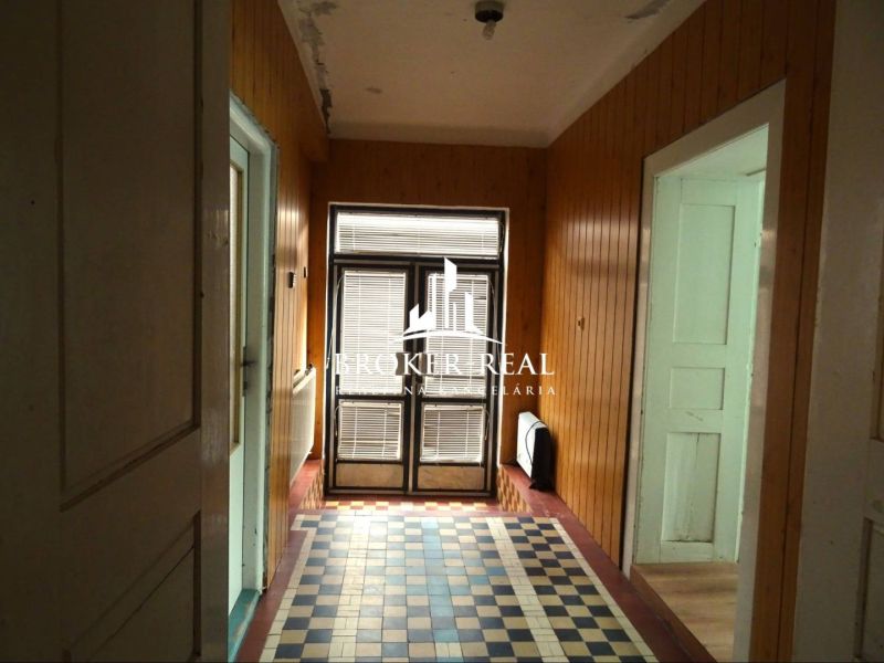 Wooden wall paneling and patterned flooring in the hallway of a family house.