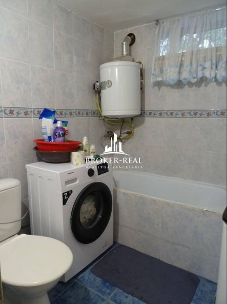 A bathroom in a family house with a shower, a washing machine, and a gas boiler.