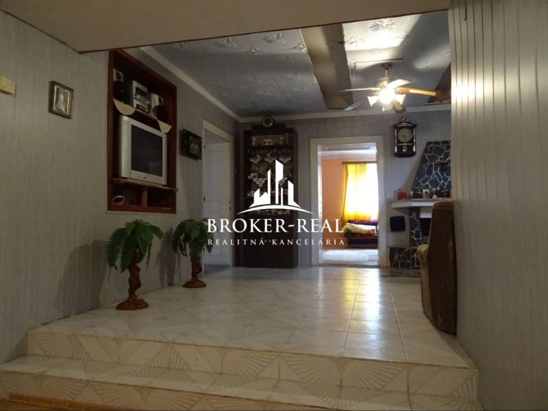 Living room in a family house with white walls and a ceiling fan.