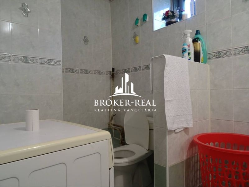 Bathroom in a family house with a washing machine, toilet, and cleaning products.