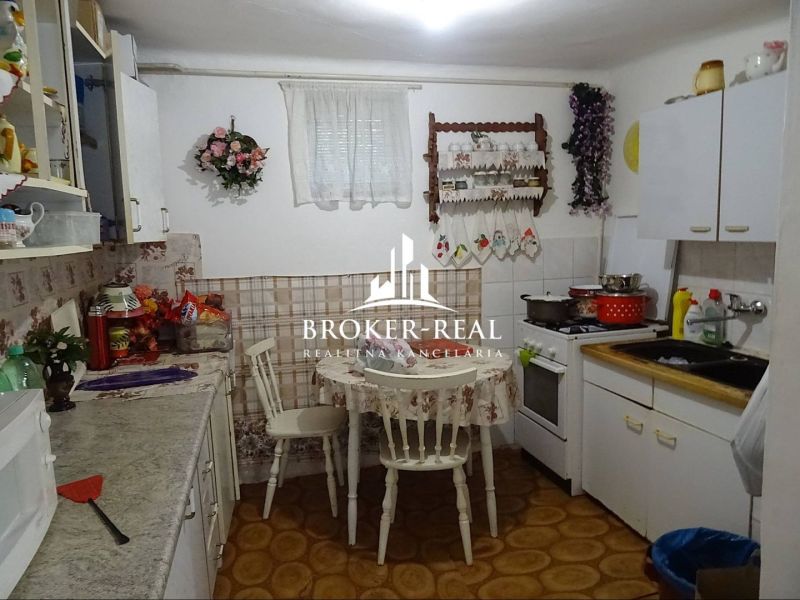 A kitchen in a family house with simple furnishings, floral decorations, and a gas stove.