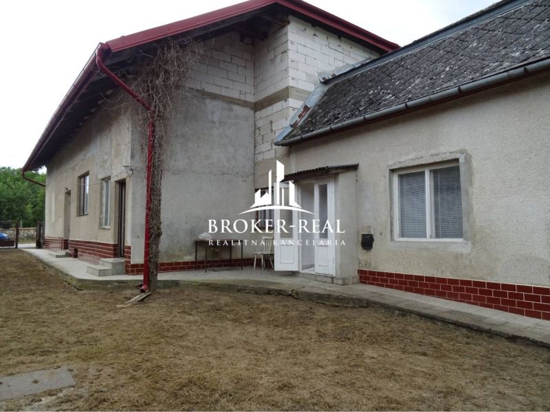 A family house in Sirník with an unplastered brick extension and a metal roof.