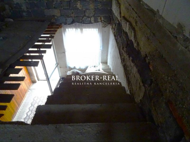A staircase in the interior of a family house with a stone wall and wooden elements.