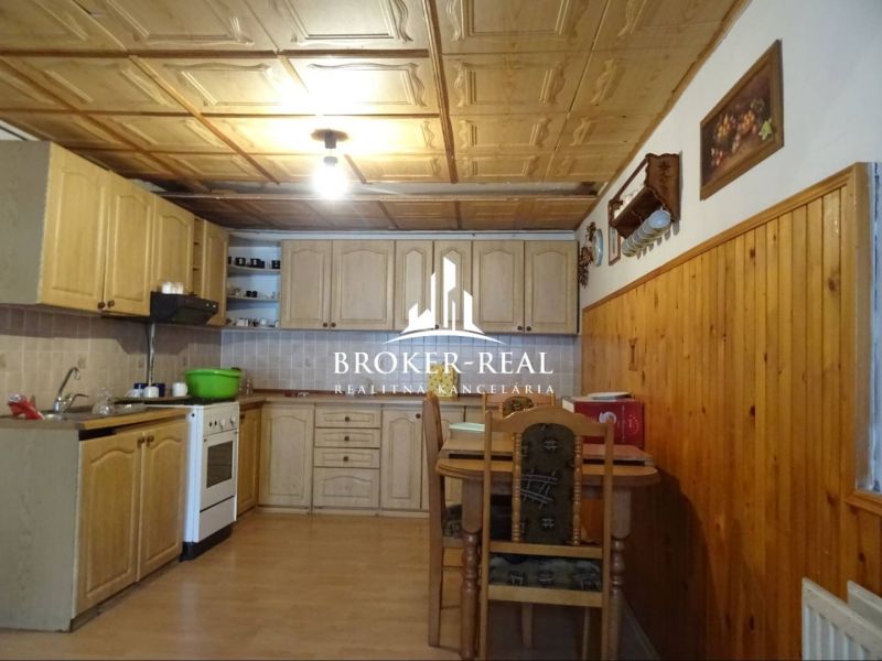 A kitchen in a family house with a wooden decor floor and a wooden ceiling.