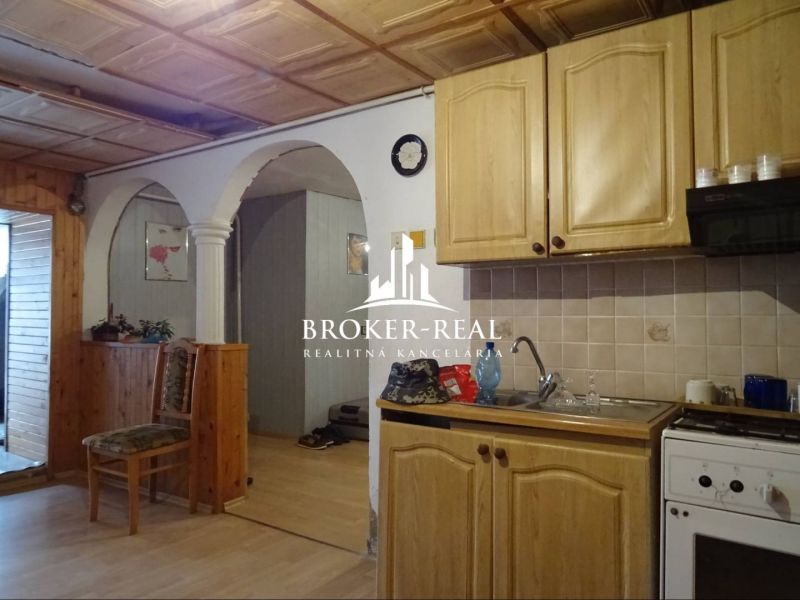 A kitchen with an arched doorway, wooden cabinets, a floor with a wooden design, family house.