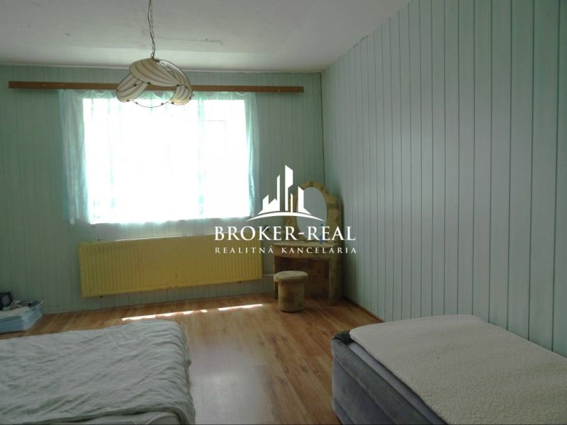 A room in a family house with a wooden decor floor and green walls.