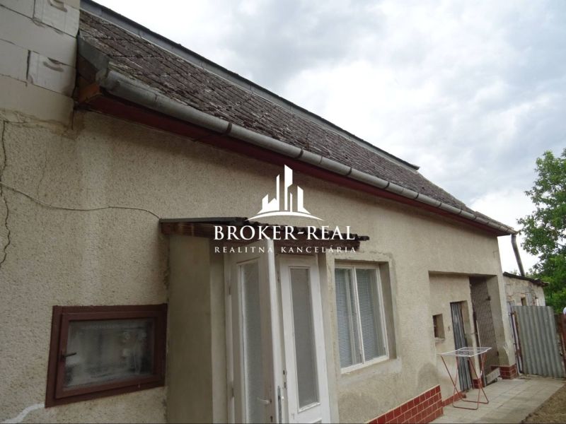 A family house in Sirník with traditional plaster and a sloped roof under an overcast sky.