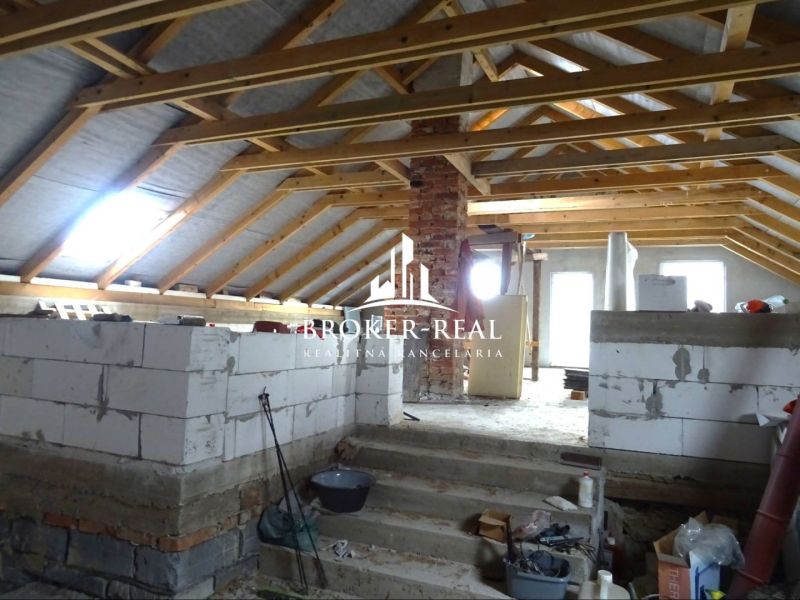 An unfinished attic space in a family house, with visible wooden beams and construction materials.