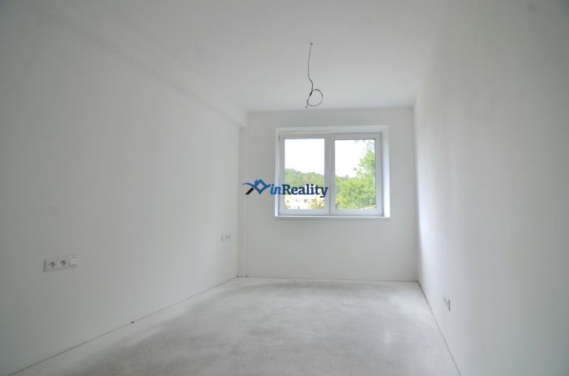 A spacious room with a large window in a 2-room apartment.